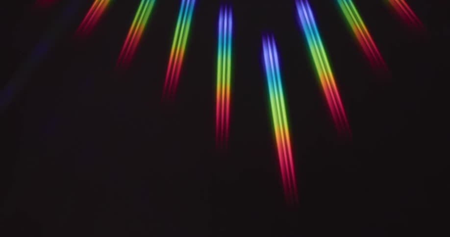 Rainbow rays of light reflect on a black surface