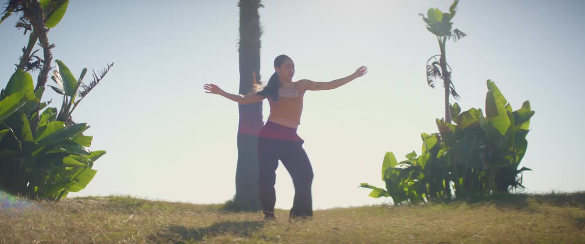 Woman with long hair dances outdoors near tree