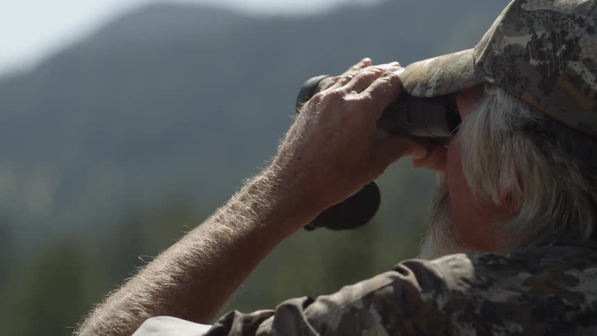 A man looks over the horizon with binoculars