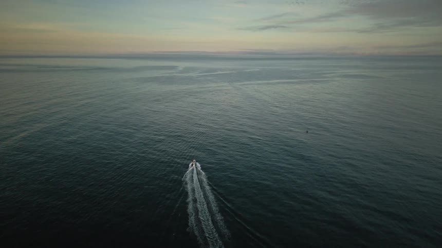 A boat leaves a trail behind as it sails across open water