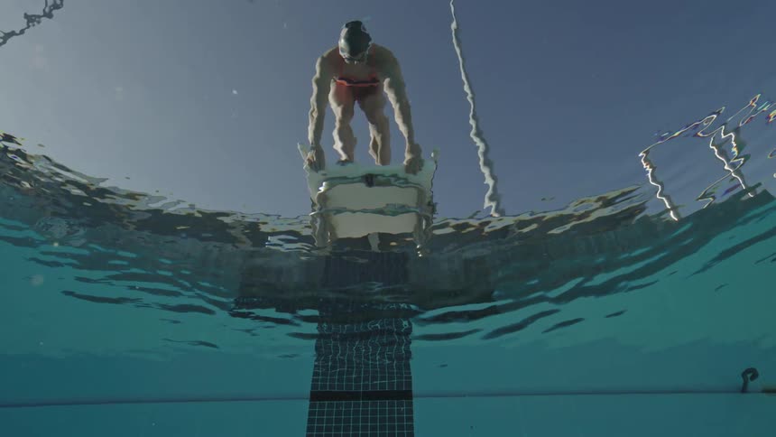 A woman stands at the foot of a diving board to dive in the pool