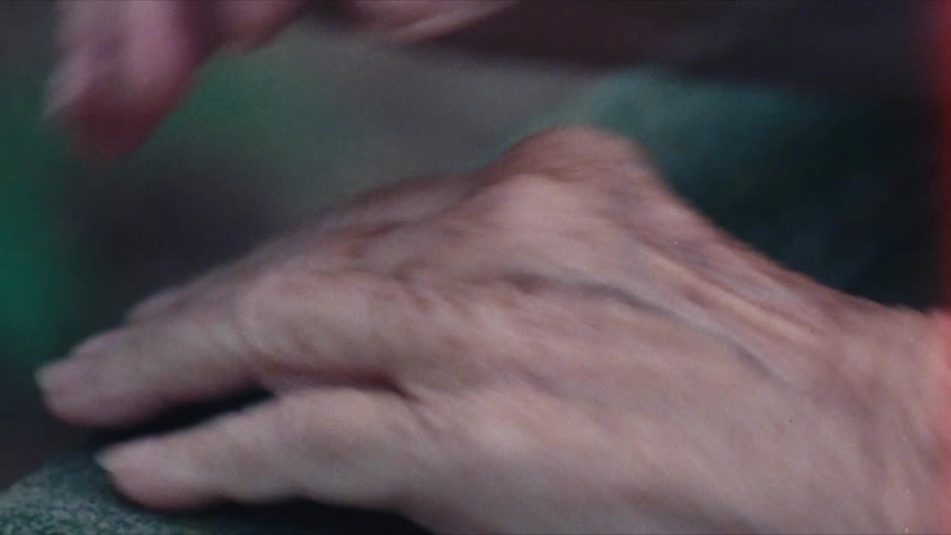 An elderly place her hands together while wearing a ring