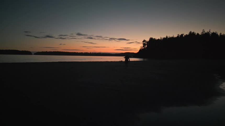 Person running on the beach with the sunrise on the horizon