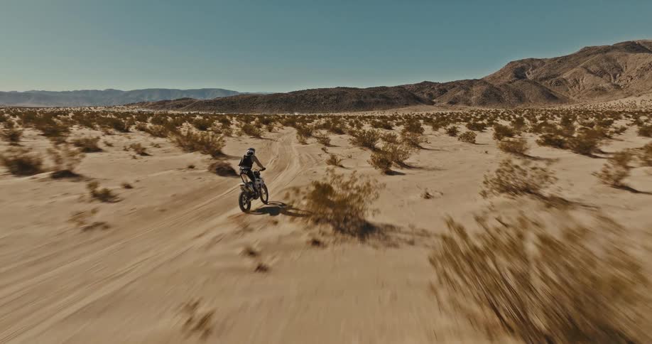 A man weaves through the desert landscape on his motorcycle
