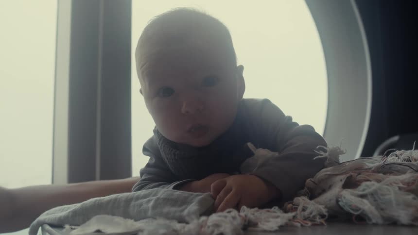 Baby resting over a blanket near a window