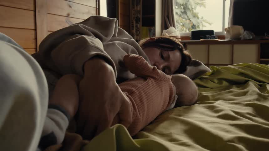 Mother lying on the bed with her baby daughter