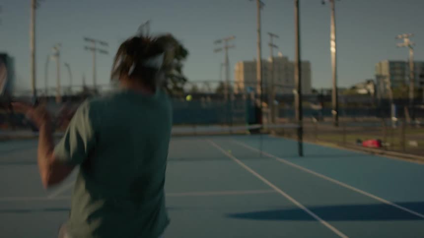 Man playing tennis with his back turned on an open court
