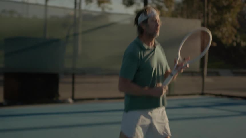 A man playing a tennis match at evening