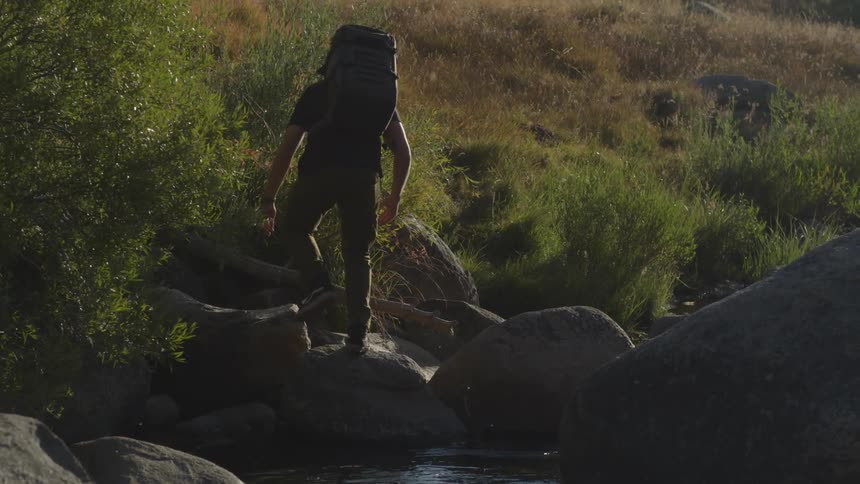 A man gets up and jumps over to a rock
