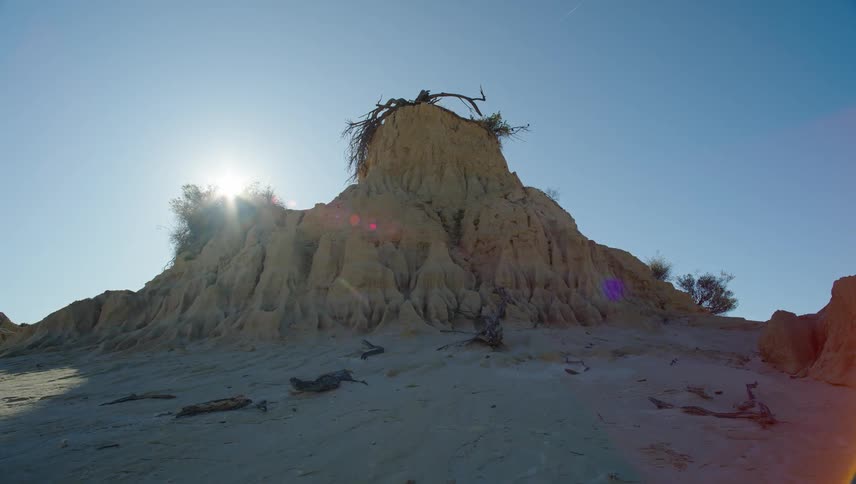 The sun hiding behind a rock formation in the desert