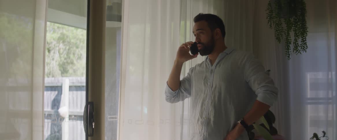 A man by a window talking on the phone