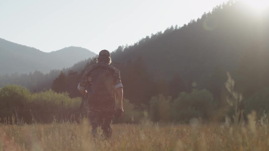 A man is hiking through tall grass