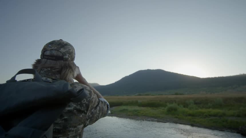 A man is looking around a valley with binoculars