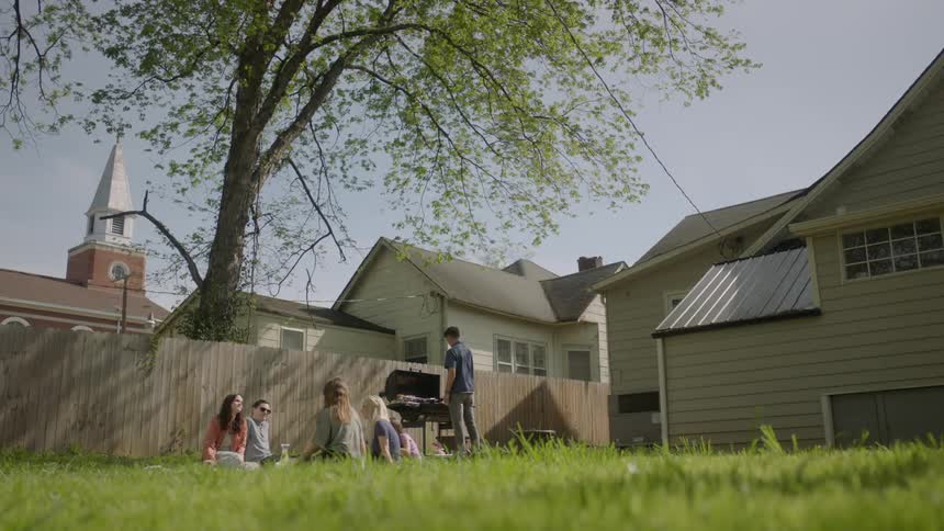 People are sitting in the grass having a barbecue