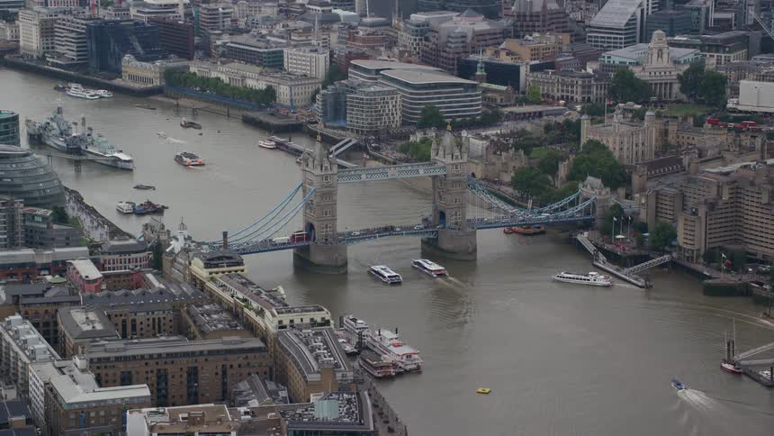 A city with a bridge over a river as boats drive by with some docked at bay