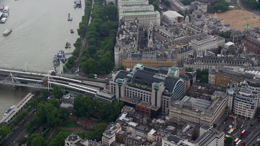 Trains move through the charing cross railway station london as traffic moves on the roads along the coast and ships sail in the water