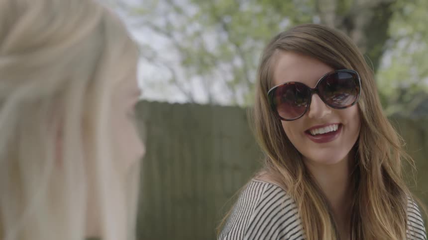 Two women talk sitting in a yard