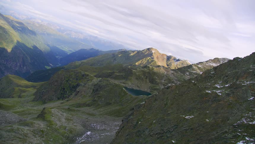 An aerial view of mountain peaks and a lake at the top of one of them