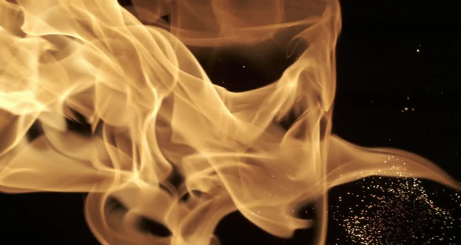A flame rippling in the dark releasing sparks