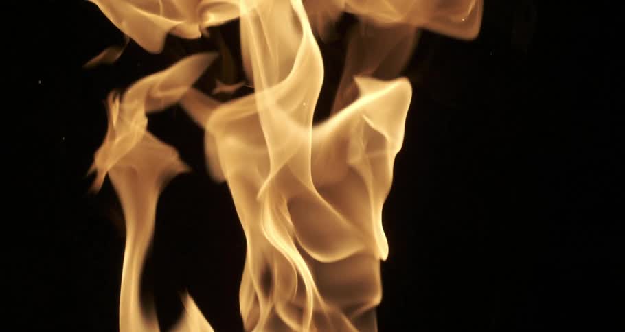 Glowing sparks and embers float among orange flames as they rise in the darkness