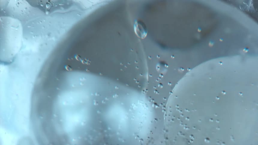 Clear beverage fizzes around spherical ice cubes