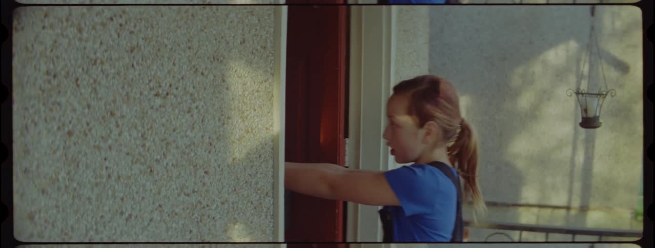 A woman coming out of a door with a firearm and pointing it upwards