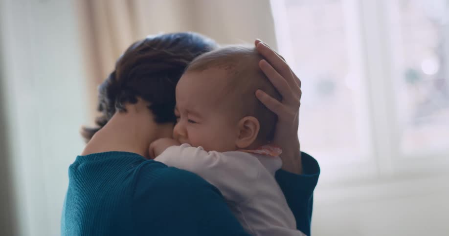 A mother tries to comfort her crying baby by holding and rocking her