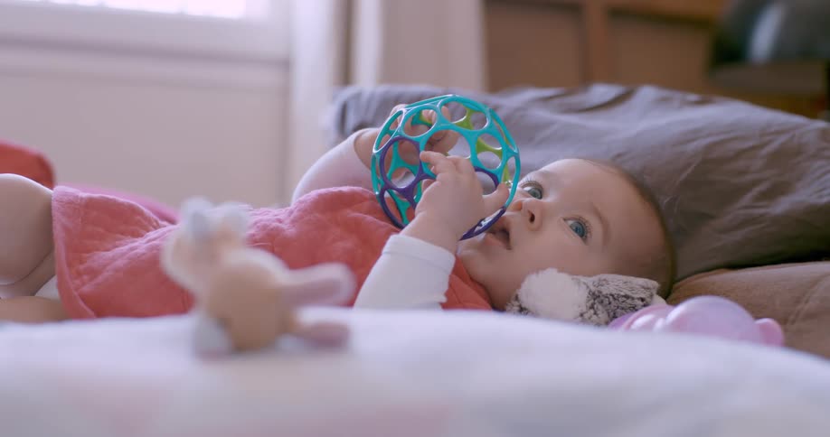 Closeup of a baby lying on the bed playing with a toy