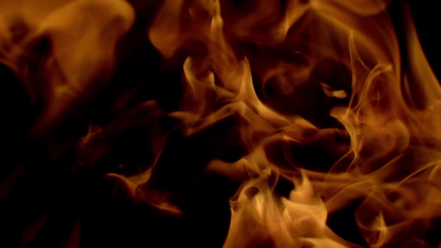 A flame of golden fire in a smoky shape on a black background