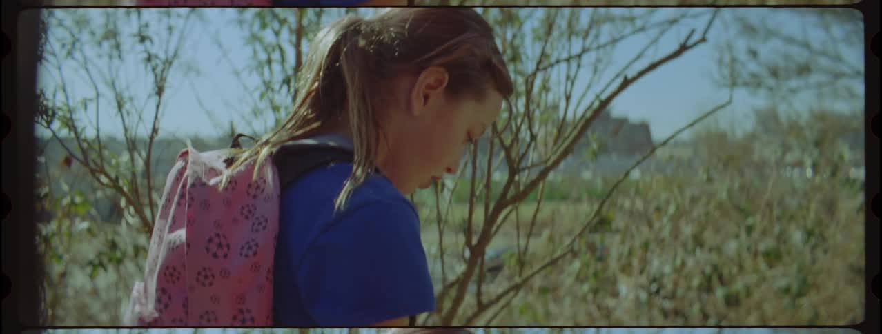 A girl picks up a teddy bear on the trail