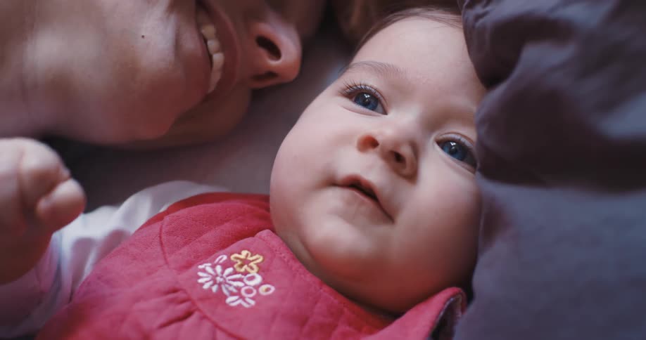 Mother smiles while lying down and cuddling daughter