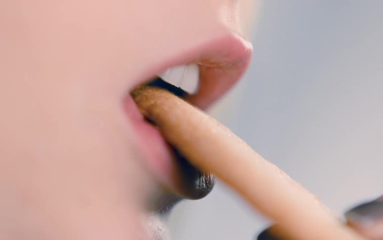 A womans mouth is shown slowly biting a cookie