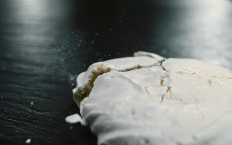 Powder flies as a cookie falls on to a table and breaks