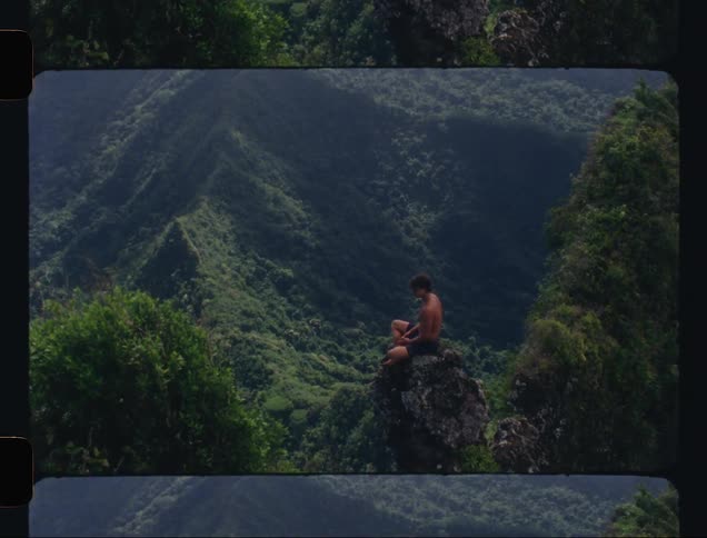 A shirtless man sitting and thinking on a rock in a mountain