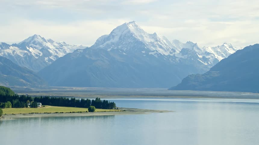 A landscape of a lake and behind huge mountains with their snowy peaks and Mt Cook New Zealand highest mountain