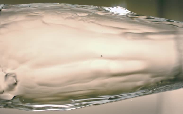 A liquid moving to the right around a transparent object