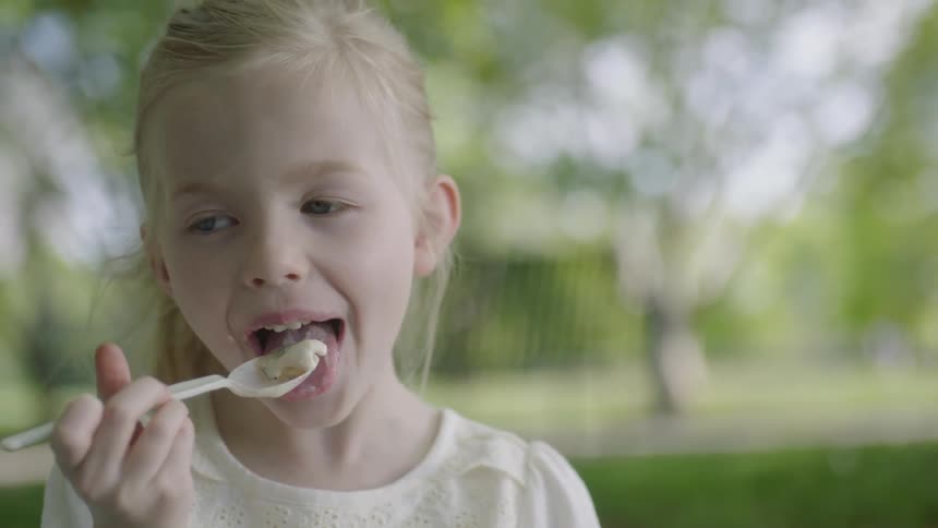 A girl eats some food from a spoon