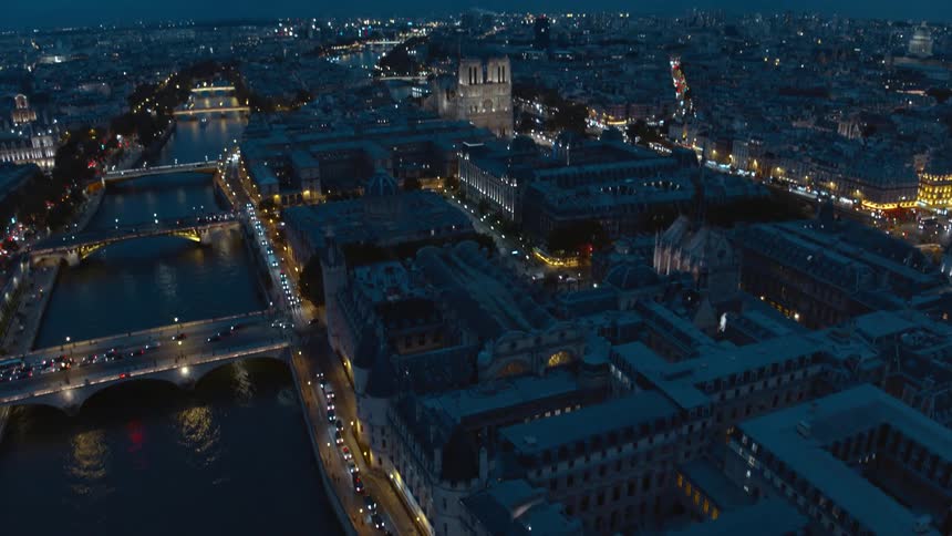 Traffic crosses bridges on river curving through city scape at night