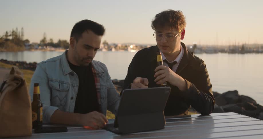 Two men sitting at the outdoor table using their laptop