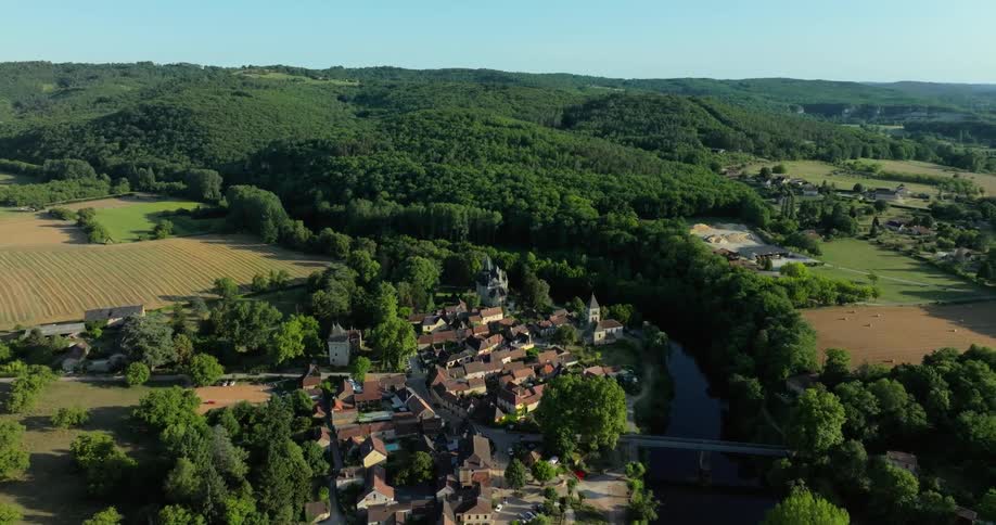 River winds through small town passing crop fields and forest