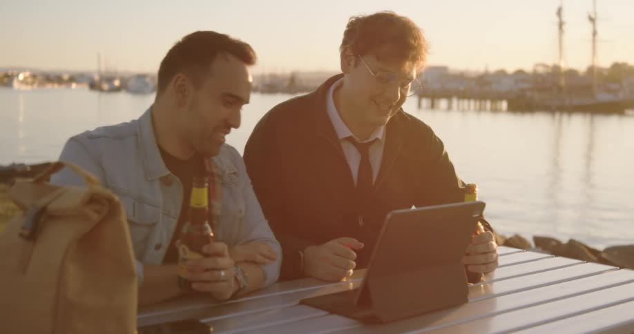 Two men talking and drinking outdoors