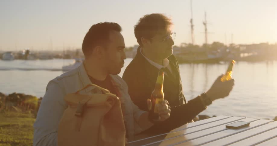 Two men sitting at the table drinking outdoors