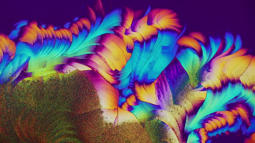 Colorful crystals growing and forming abstract shapes under microscope