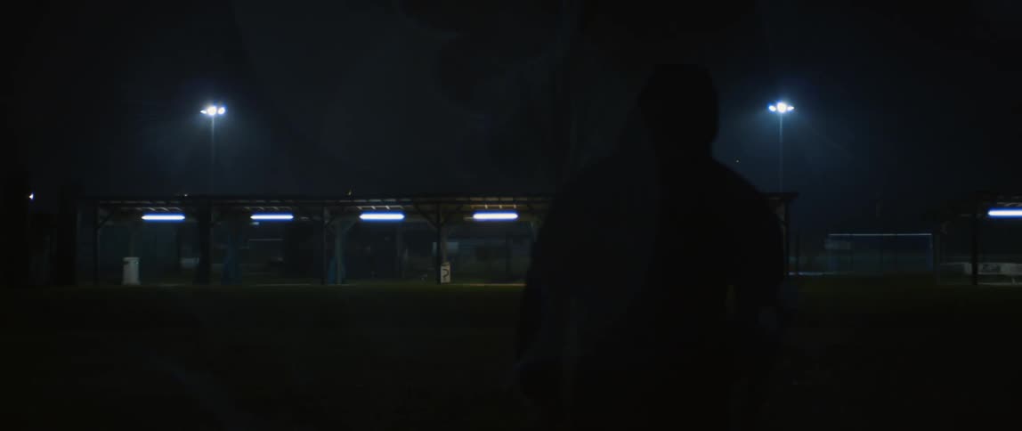 A person walks on a sports field at night