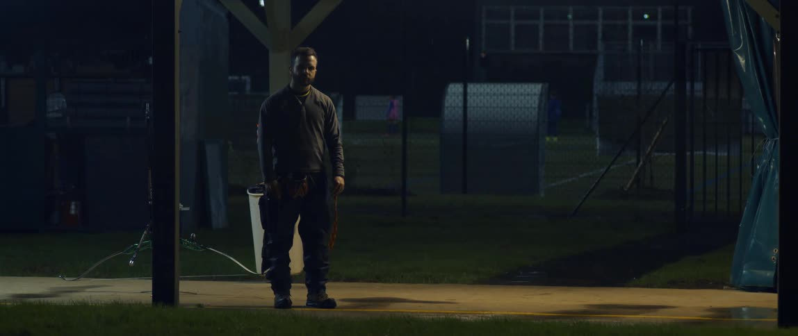 A man stands on a sidewalk and stares at night