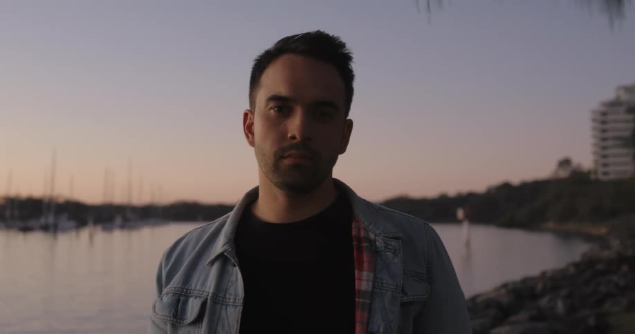 A man is standing by the shore at sunset
