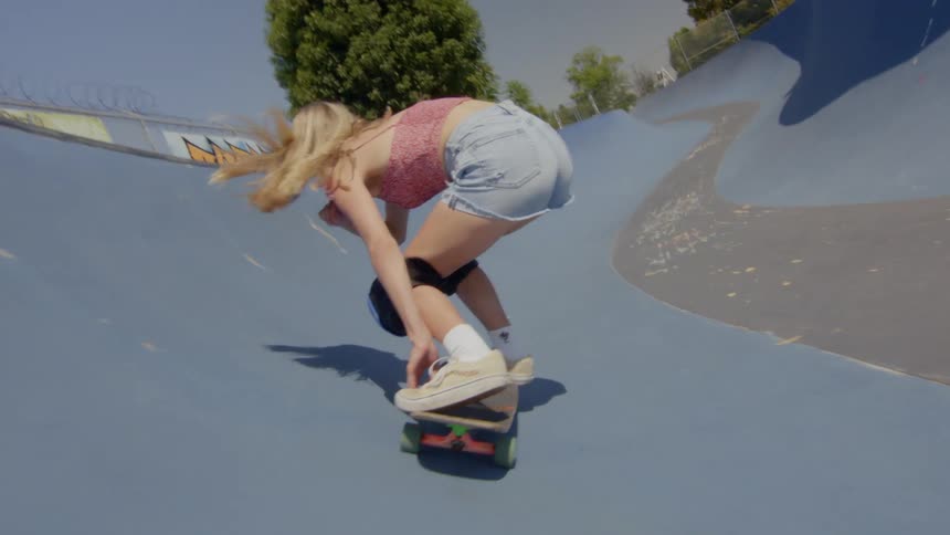 A blonde woman is skateboarding on a small rink