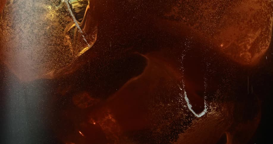 Small bubbles rises through ice cube filled beverage