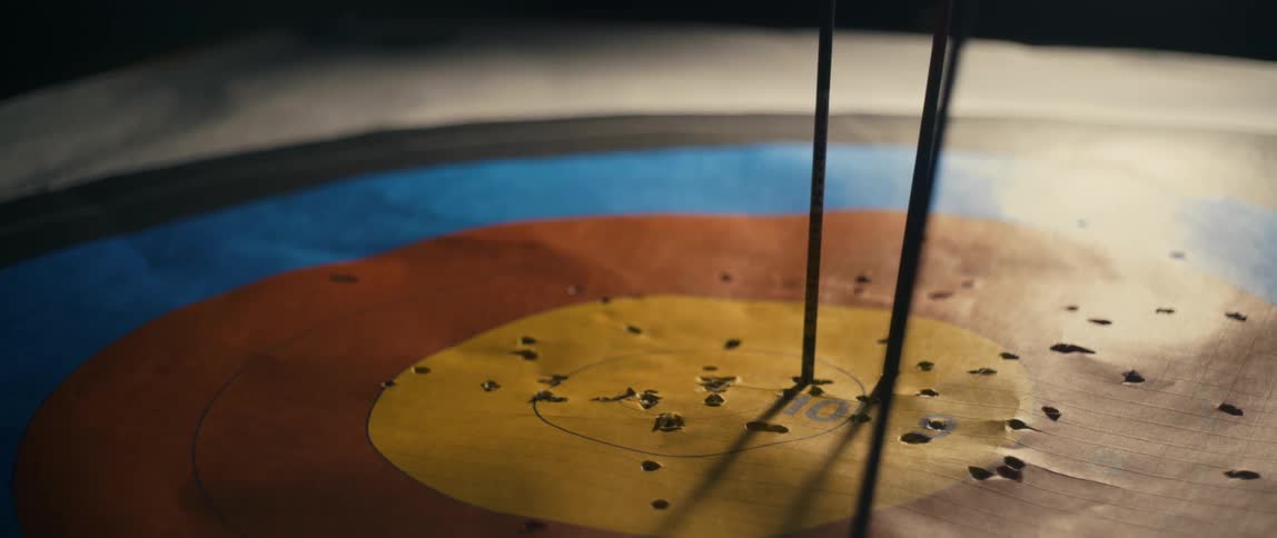 A man removing arrows from the target board at night