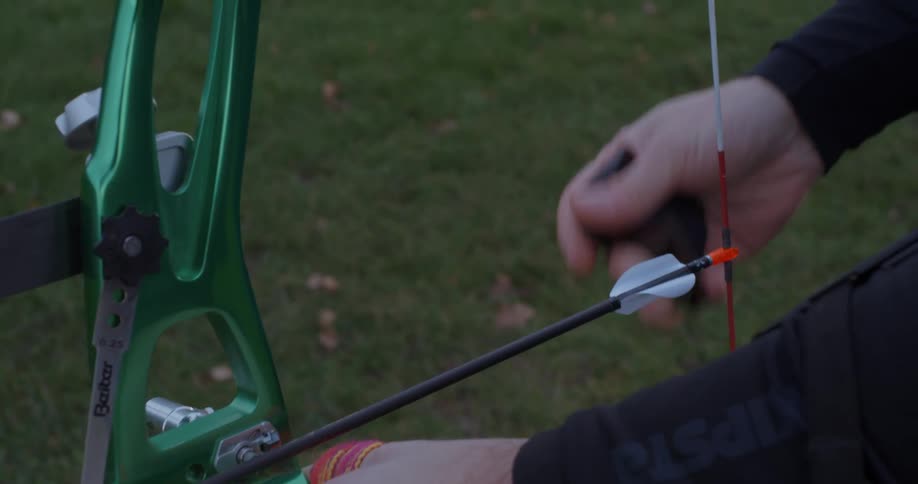 A man holds a bow and arrow and pulls the arrow back